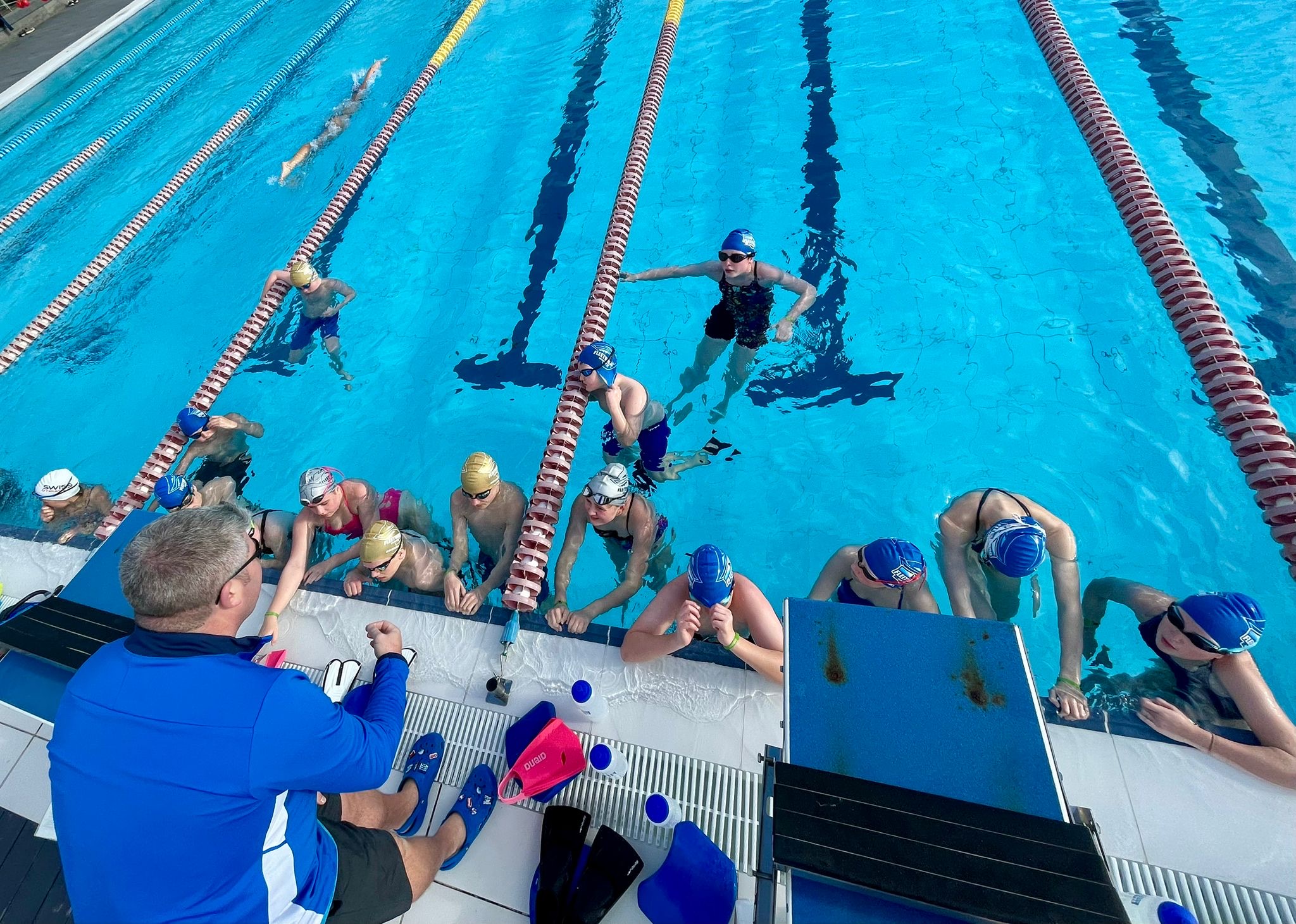 A Makos coach talking with athletes beside the pool